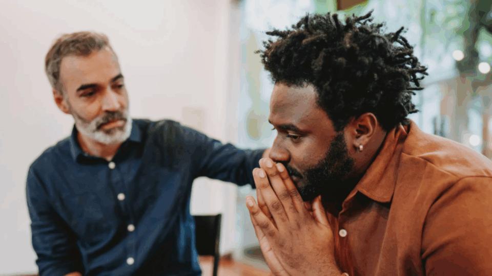 a man comforting another man with his hand on his shoulder