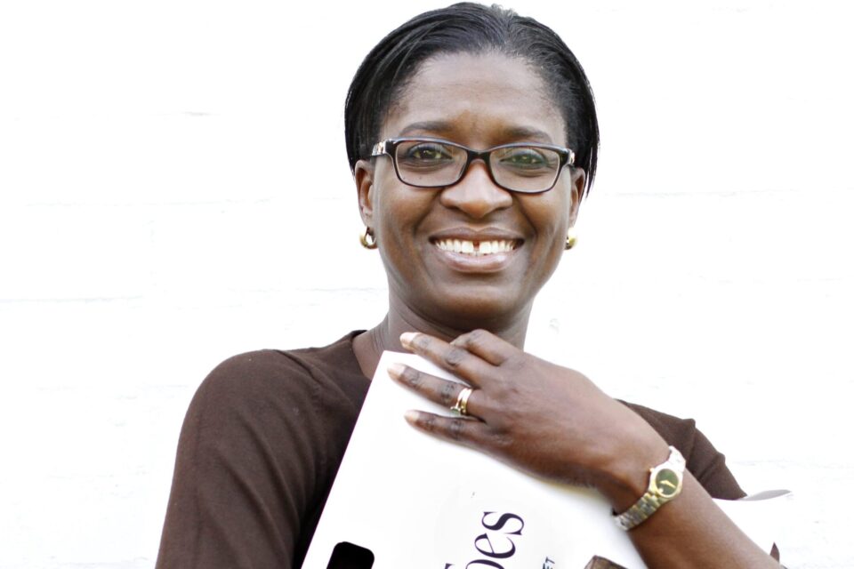 A smiling woman holding packaging for 'Snug Toes' - heatable slippers