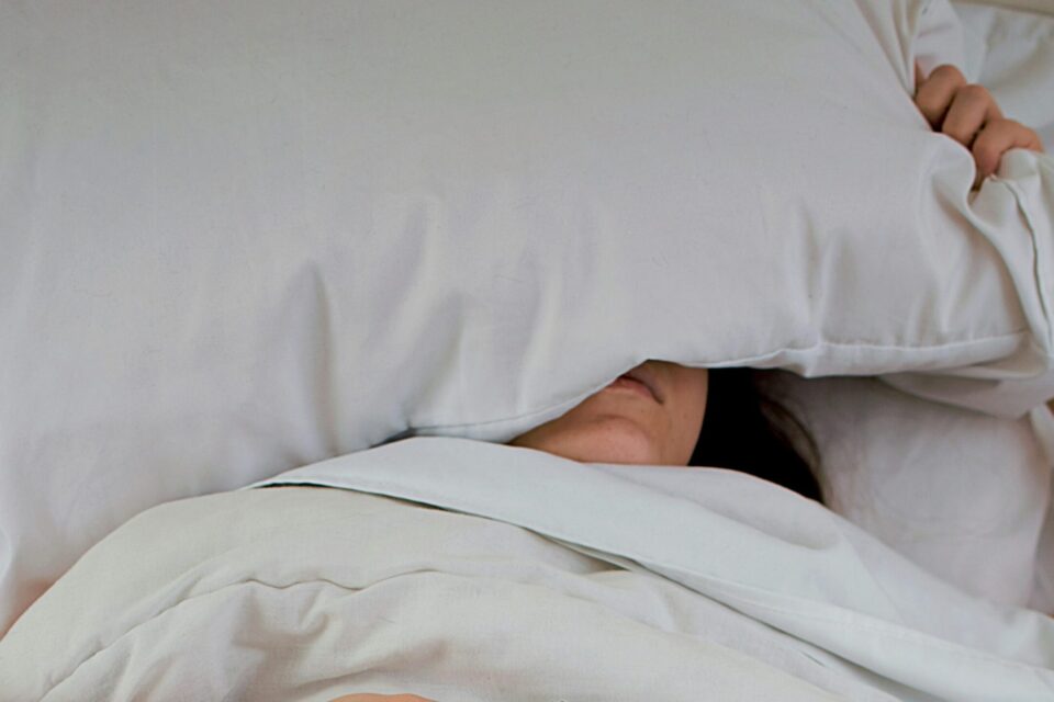 Person in bed with head under pillow