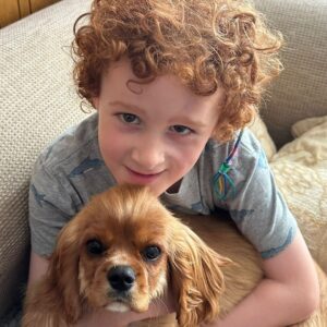 Young boy holding small dog on his lap