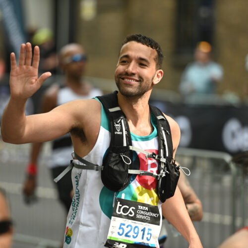 a runner wearing an SRUK vest, waving and smiling at the crowd
