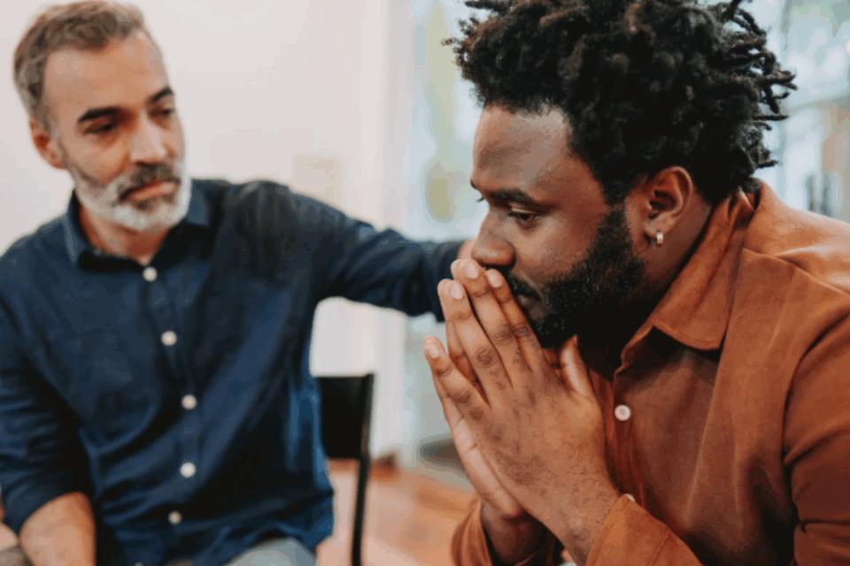 a man comforting another man with his hand on his shoulder