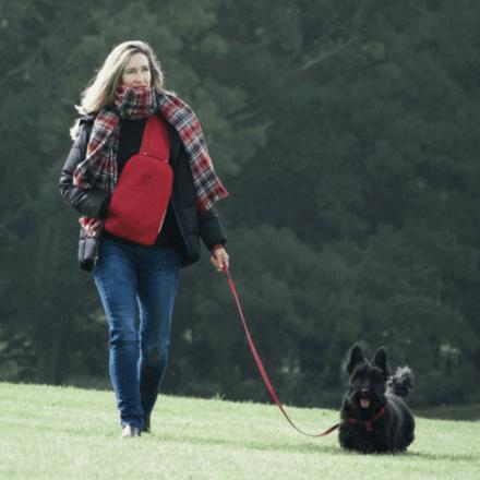 A woman walking with a dog outside wearing a SnugBud