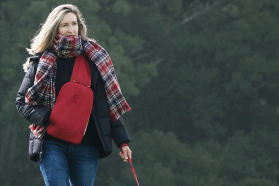 A woman walking with a dog outside wearing a SnugBud