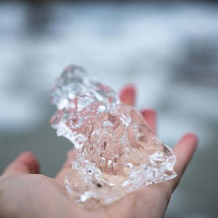 a hand holding a large chunk of clear ice